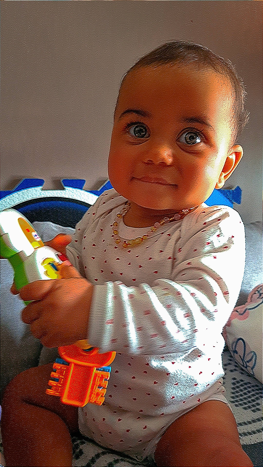 Ambre participe au concours pour gagner de l'argent avec cette photo : baby, baby_toddler_clothing, cheek, child, eyelash, finger, happy, mouth, nail, neck, nose, pattern, person, plastic_bottle, sitting, skin, sleeve, t_shirt, thigh, toddler