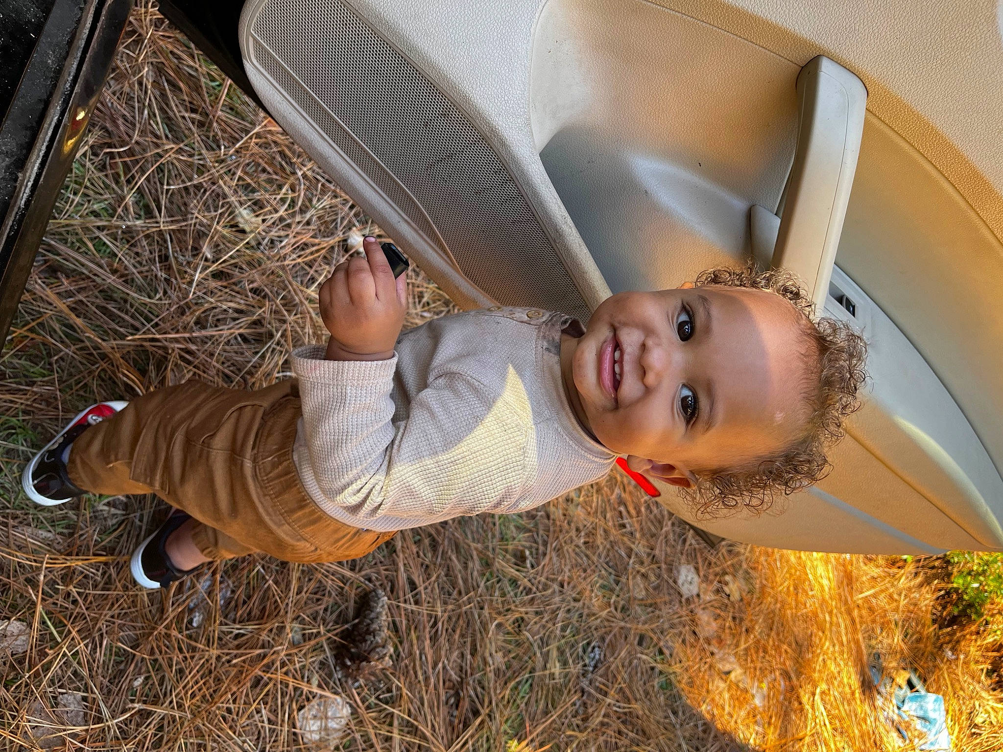 Andre is registered to the contest to win money with this photo: baby, child, comfort, fun, grass, happy, hat, joy, leisure, people_in_nature, person, plant, sitting, smile, soil, sun_hat, toddler, tree, wood