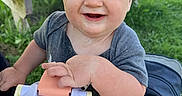 Benny is registered to the contest to win money with this photo: baby, bench, blond_hair, blue_eyes, child, close_up, daylight, family, grass, gray_shirt, happy, infant, outdoor, park, picnic, portrait, sippy_cup, sitting, smiling, stroller
