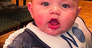 Magnus joined the competition — help win amazing prizes! baby, child, infant, bib, clothing, face, blue_eyes, expression, fluffy_blanket, indoor, furniture, chair, table, wooden_floor, person, cute, portrait, sitting, mouth_open, pink_cheeks