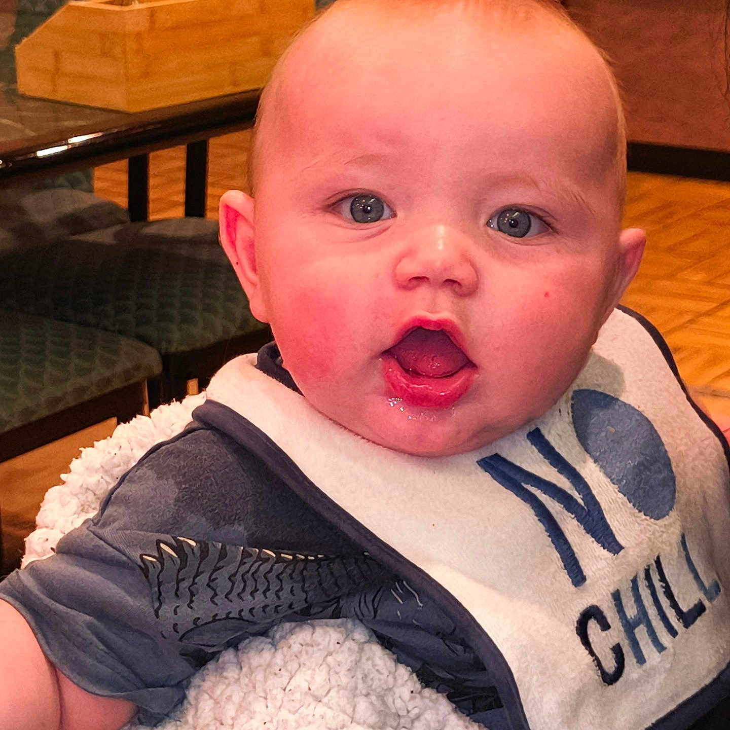 Magnus joined the competition — help win amazing prizes! baby, child, infant, bib, clothing, face, blue_eyes, expression, fluffy_blanket, indoor, furniture, chair, table, wooden_floor, person, cute, portrait, sitting, mouth_open, pink_cheeks