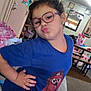 Ezra joined the competition — help win amazing prizes! child, glasses, blue_shirt, cartoon_bear, puckered_lips, posing, indoor, living_room, colorful_drawings, furniture, carpet, mirror, earrings, toy, wall_art, hand_on_hip, hair_tied, smiling, person, home