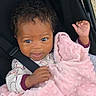 Jadiyah is registered to the contest to win money with this photo: baby, child, blanket, pink, curly_hair, stroller, seatbelt, clothing, infant, cute, face, portrait, hand, soft_texture, indoor, comfort, smile, young, person, toddler