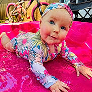 Emmalee is registered to the contest to win money with this photo: baby, child, toddler, swimsuit, headband, pink_pool, water, bicycle, outdoor, play, summer, splashing, colorful_clothing, rosy_cheeks, blue_eyes, folding_chair, sunlight, backyard, fun, happy