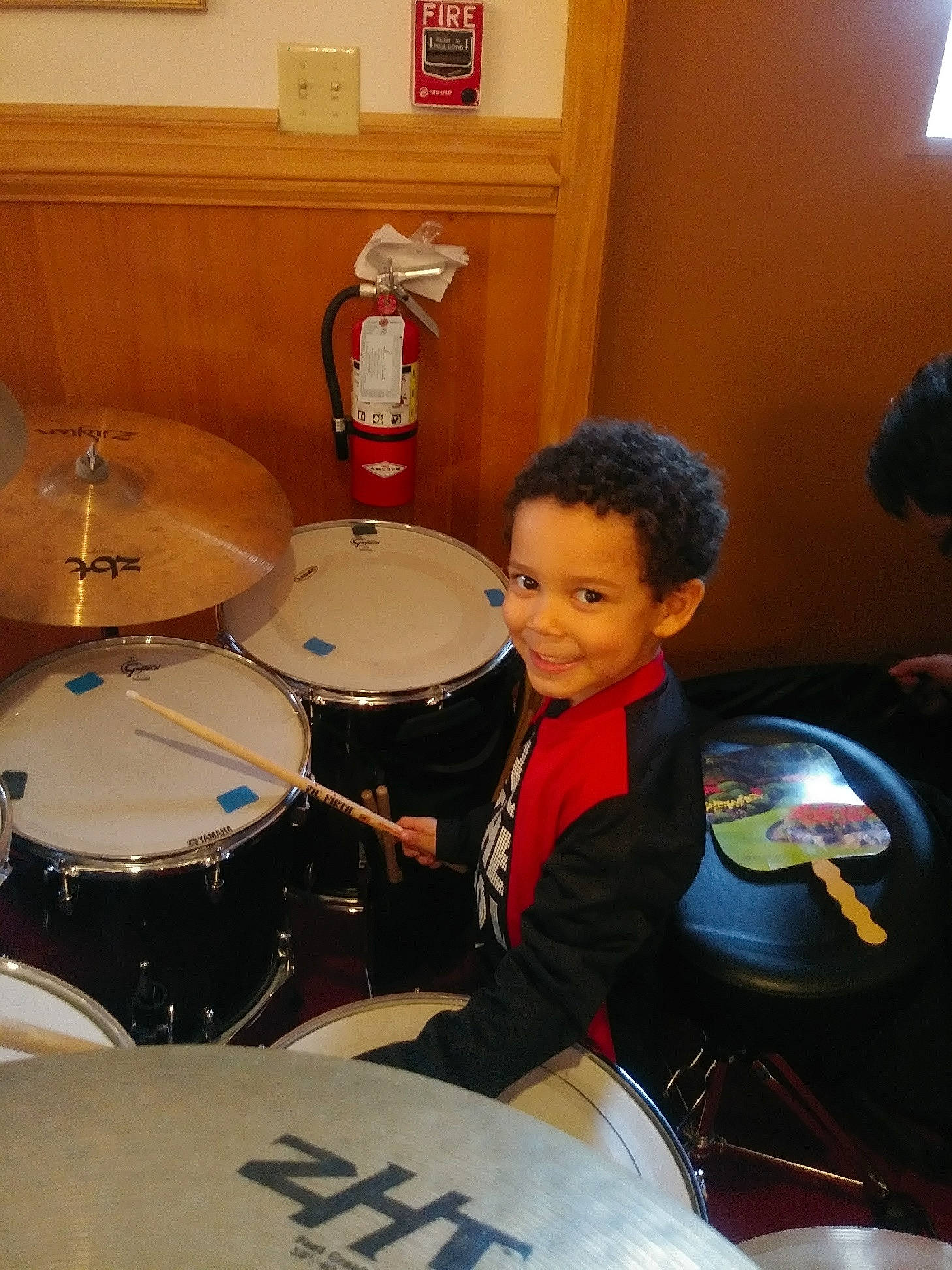 Keagan is registered to the contest to win money with this photo: automotive_tire, bass_drum, drum, drum_stick, drumhead, drummer, event, fun, idiophone, joy, membranophone, musical_instrument, musical_instrument_accessory, musician, percussion, percussionist, person, picture_frame, room, smile