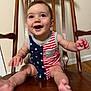 Carson joined the competition — help win amazing prizes! baby, child, smiling, happy, sitting, wooden_chair, stars, stripes, american_flag_pattern, clothing, indoor, person, cute, infant, legs, hands, face, eyes, mouth, wood_floor