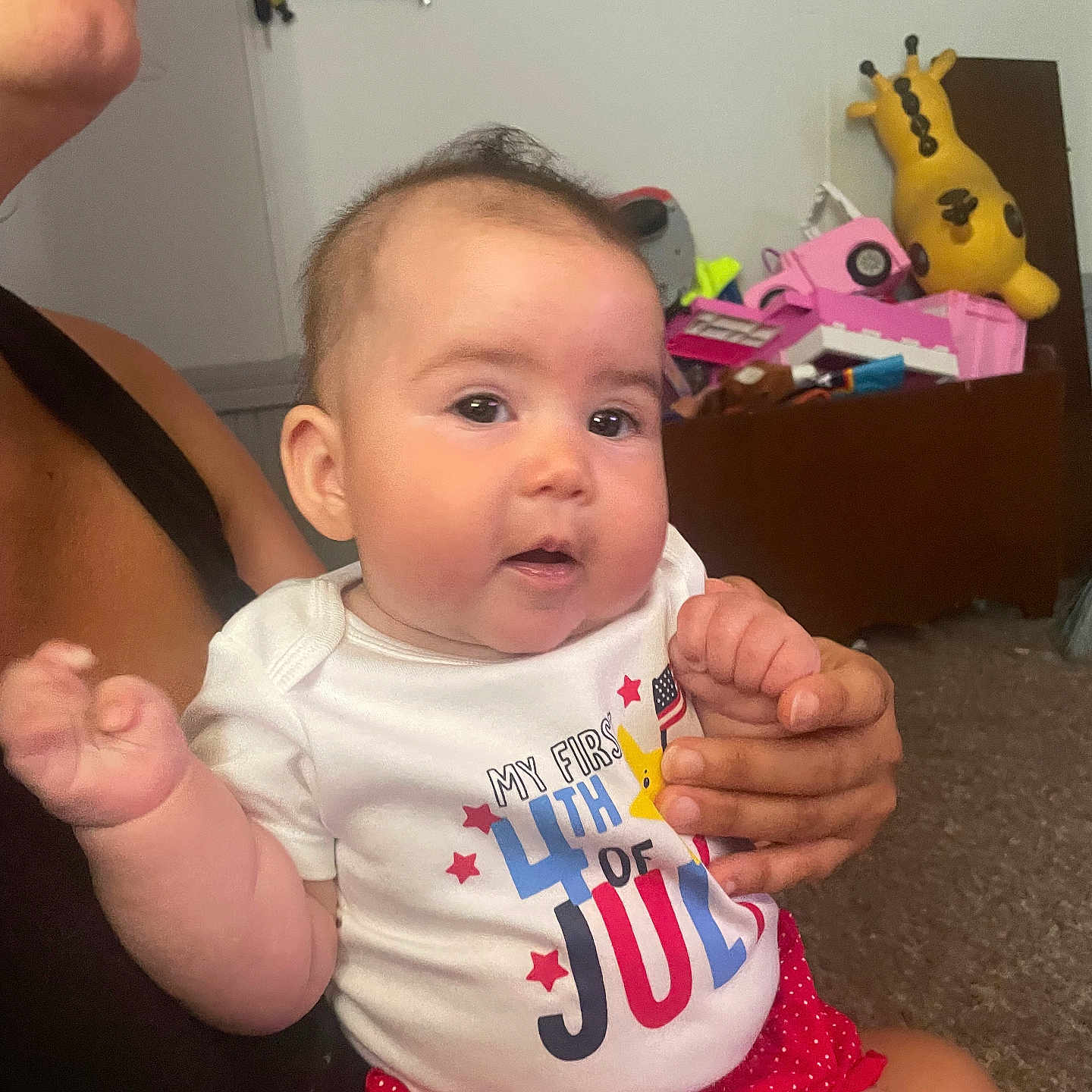 Leah is registered to the contest to win money with this photo: 4th_of_july, adult, baby, carpet, celebration, child, clothing, cute, eyes, face, giraffe_plush, hand, indoor, infant, mouth, onesie, person, polka_dots, red_shorts, toys