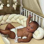 Kaïlan a rejoint le concours — aidez-le/la à gagner de superbes lots ! baby, infant, crib, diaper, plush_toys, braided_cushion, wooden_crib, hanging_toys, soft_toys, child, indoors, smiling, curious, relaxed, lying_down, cute, skin, head, hand, face