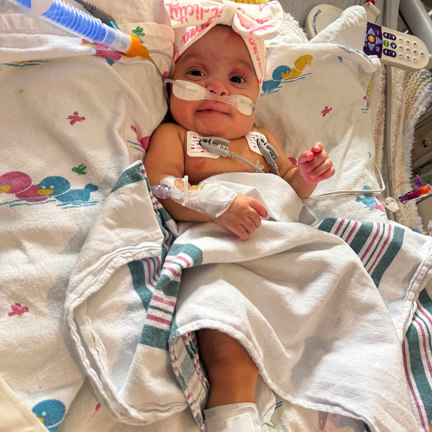 Felicity joined the competition — help win amazing prizes! baby, bandage, blanket, bow, child, cute, face, healthcare, hospital, hospital_bed, indoors, infant, lying_down, medical_equipment, medical_tubes, monitor, patient, person, smile, tubing