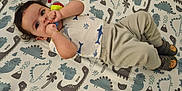 Ryland joined the competition — help win amazing prizes! baby, child, clothing, crib, cute, dinosaur_bedding, face, floor, footwear, hand, indoors, infant, lying_down, person, playful, room, sleepwear, socks, toy, wood_floor