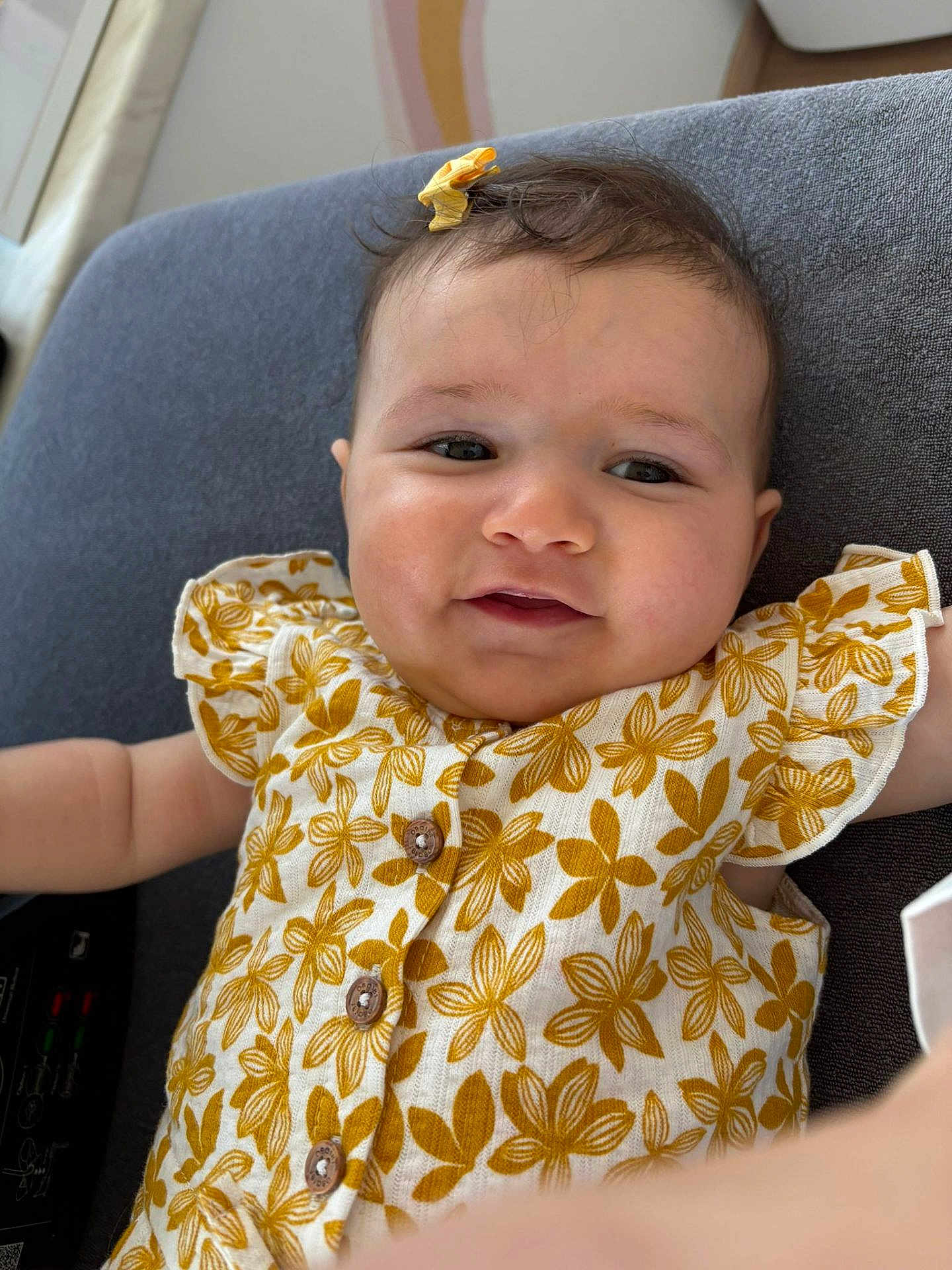 Jennah a rejoint le concours — aidez-le/la à gagner de superbes lots ! baby, child, smiling, face, hair_bow, dress, floral_pattern, cushion, button, indoor, closeup, cute, infant, person, skin, head, cheeks, eyes, arm, fabric