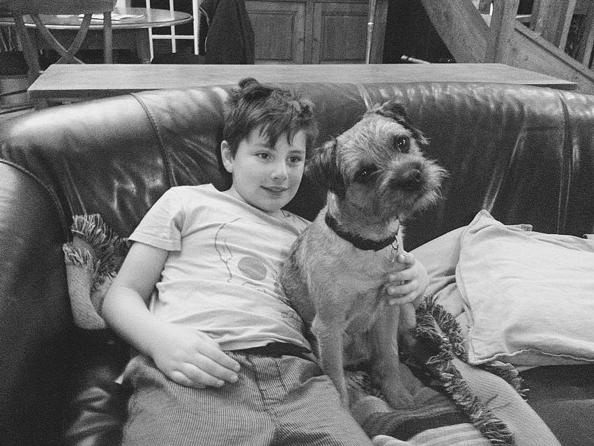 Iggy participe au concours pour gagner de l'argent avec cette photo : black, black_and_white, carnivoran, child, dog, dog_breed, dog_like_mammal, human, joy, mammal, monochrome, monochrome_photography, person, photograph, sitting, smile, snapshot, snout, style, vertebrate