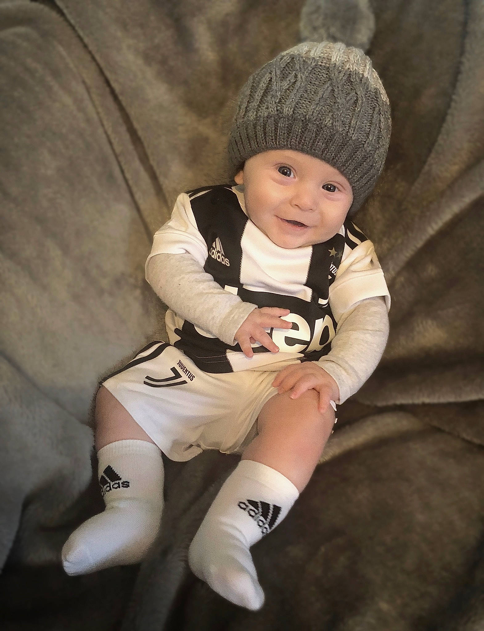 Sylver is registered to the contest to win money with this photo: arm, baby, beanie, beige, cap, child, child_model, cool, fashion_accessory, headgear, headwear, human_body, joint, leg, person, photography, product, sitting, skin, sleeve