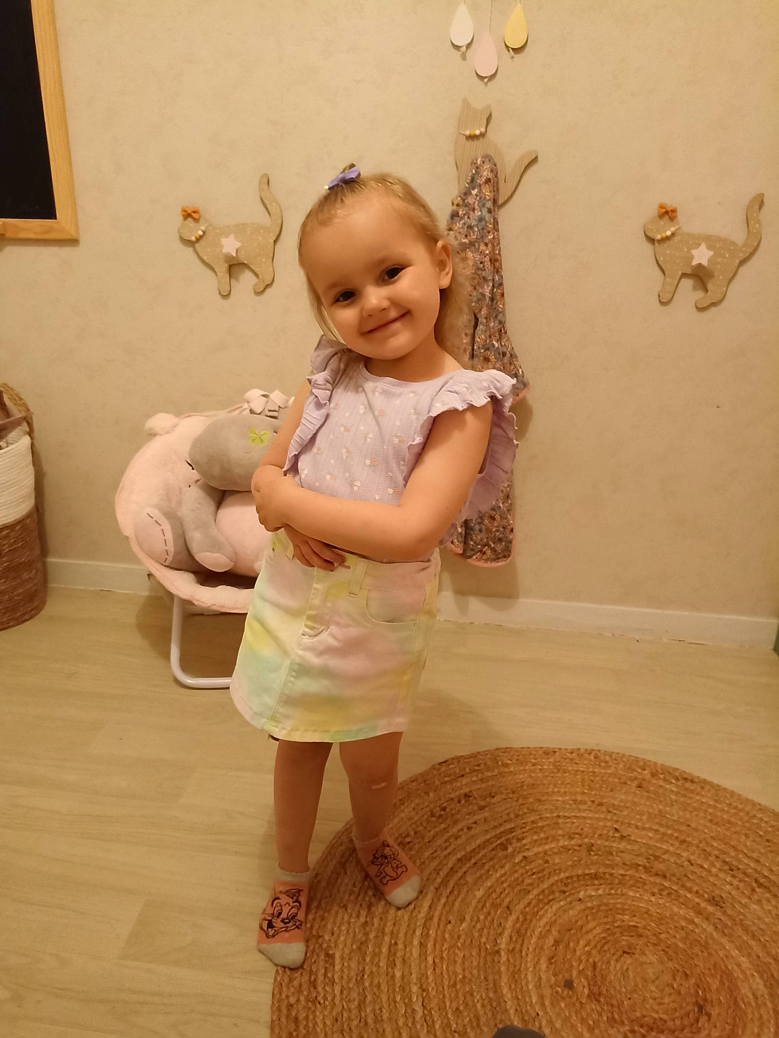 Talya participe au concours pour gagner de l'argent avec cette photo : baby_toddler_clothing, child, floor, flooring, foot, fun, happy, hardwood, human_leg, joy, pattern, person, picture_frame, room, sandal, sleeve, smile, standing, toddler, white