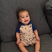 Julian joined the competition — help win amazing prizes! baby, smiling, infant, sitting, couch, clothing, overall, happy, indoor, person, face, cute, child, short_sleeves, foot, skin, human, young, relaxed, home