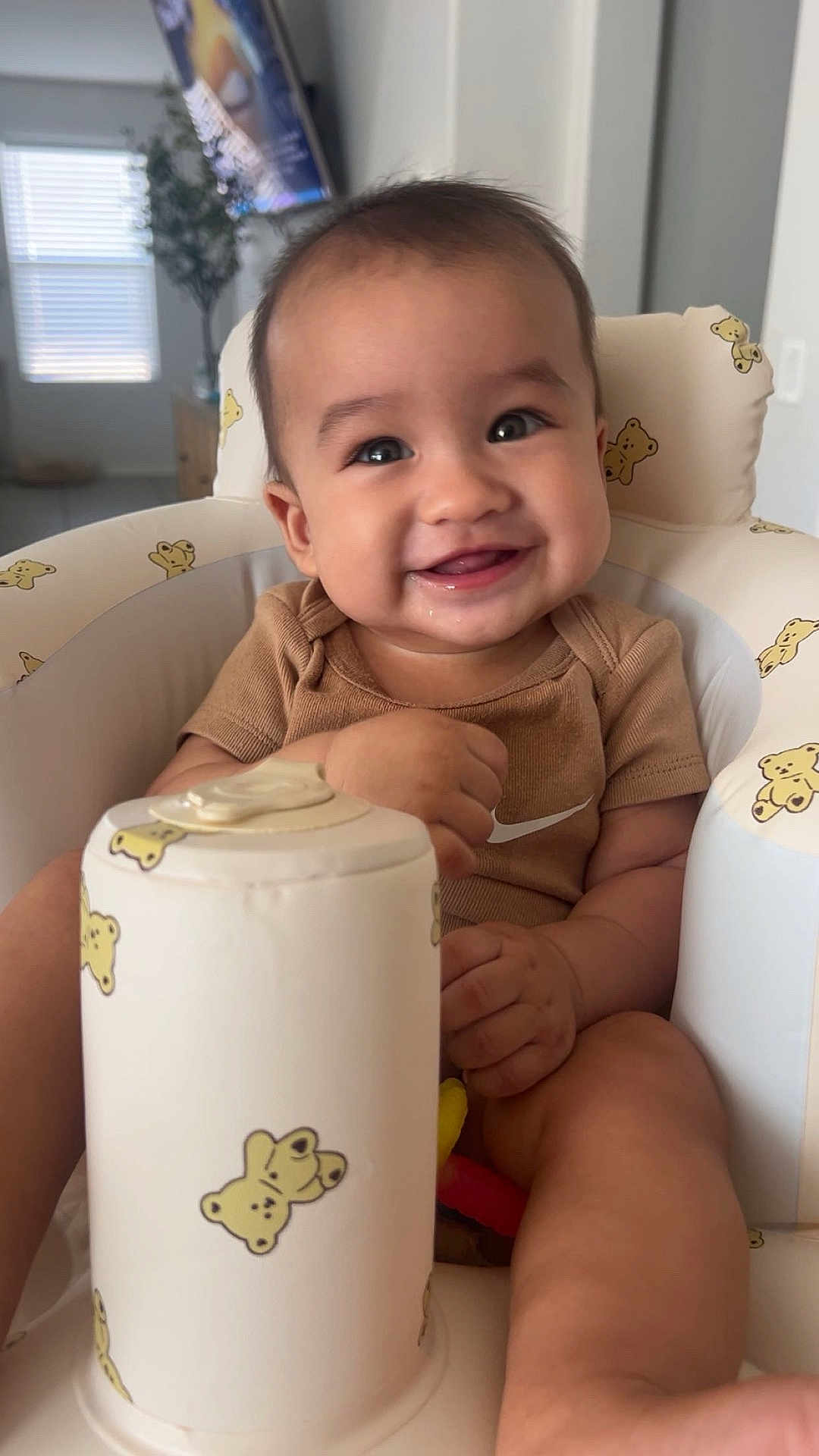Julian joined the competition — help win amazing prizes! baby, smile, child, high_chair, bear_pattern, indoor, furniture, happy, person, infant, cute, clothing, seat, toy, home, face, hands, legs, light, background