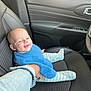 baby, child, car_interior, car_seat, blue_bib, striped_pajamas, hand_holding, denim_jacket, red_nail_polish, smiling, person, seat, steering_wheel, black_leather, door_panel, window_controls, happy, infant, young_child, portrait