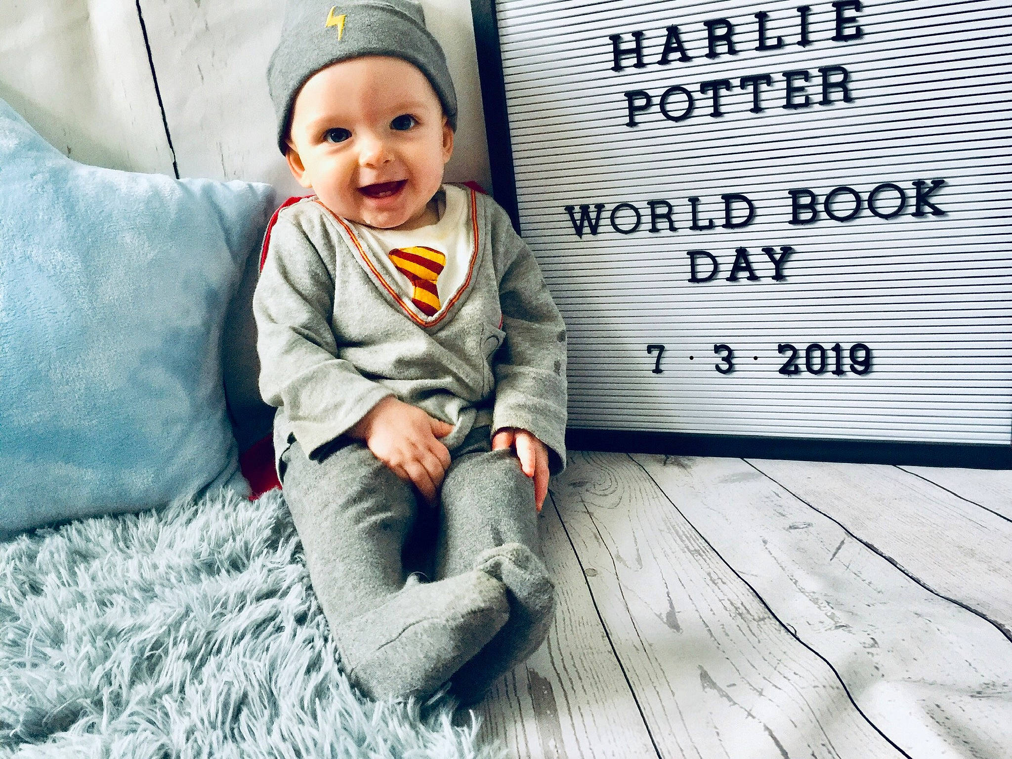 Harlie joined the competition — help win amazing prizes! baby, beanie, cap, child, cool, facial_expression, floor, flooring, happy, headgear, joy, knit_cap, outerwear, people, person, photo_caption, scarf, sleeve, smile, sweater