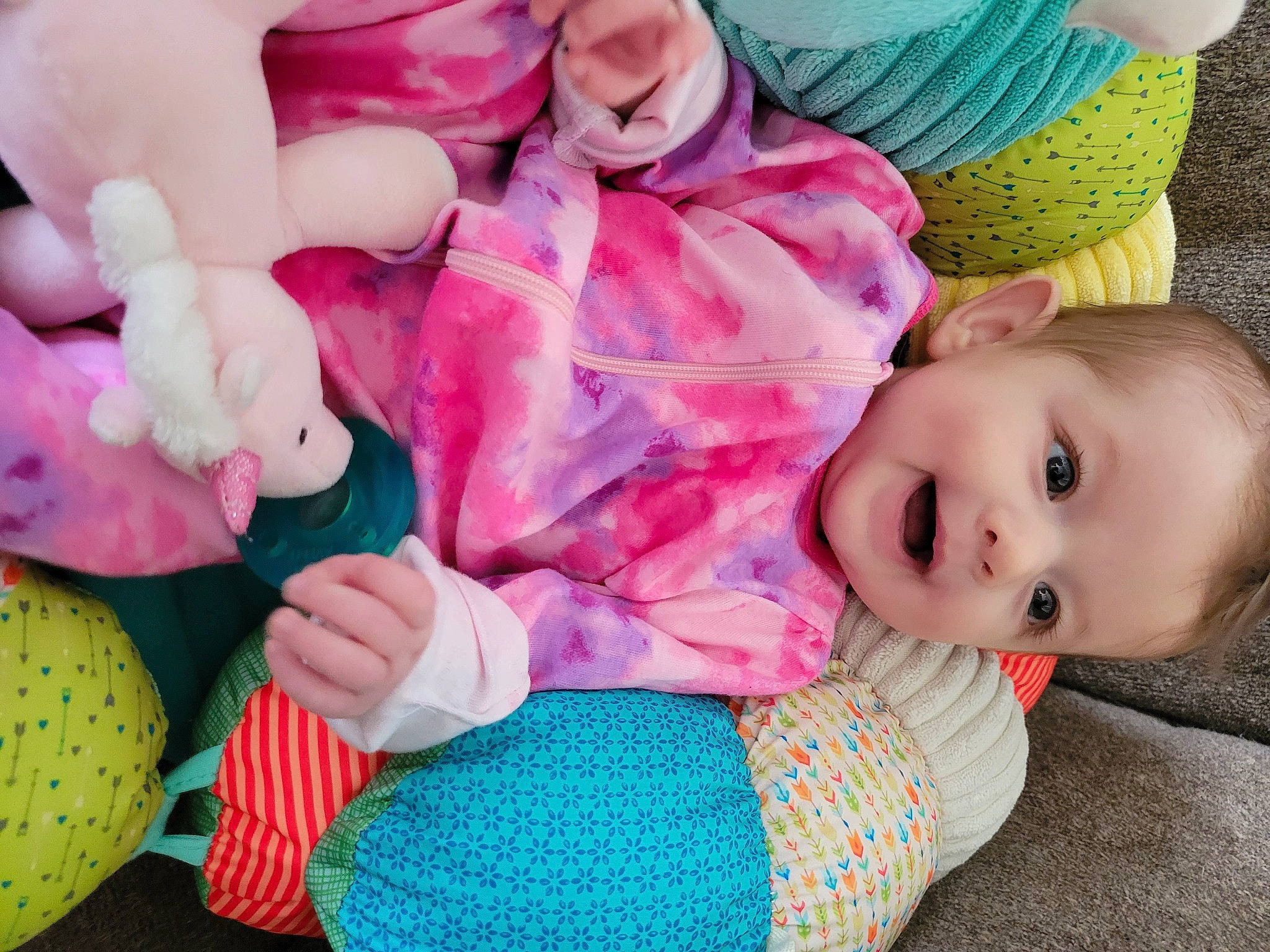 Maia is registered to the contest to win money with this photo: baby, baby_toddler_clothing, cheek, child, comfort, eye, green, hand, head, human_body, nose, organ, person, pink, purple, skin, sleeve, textile, toddler, toy