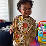 toddler, child, smiling, curly_hair, indoor, playroom, toy, colorful, barefoot, happy, clothing, jacket, lion_king, person, floor, furniture, play_mat, baby, cute, portrait