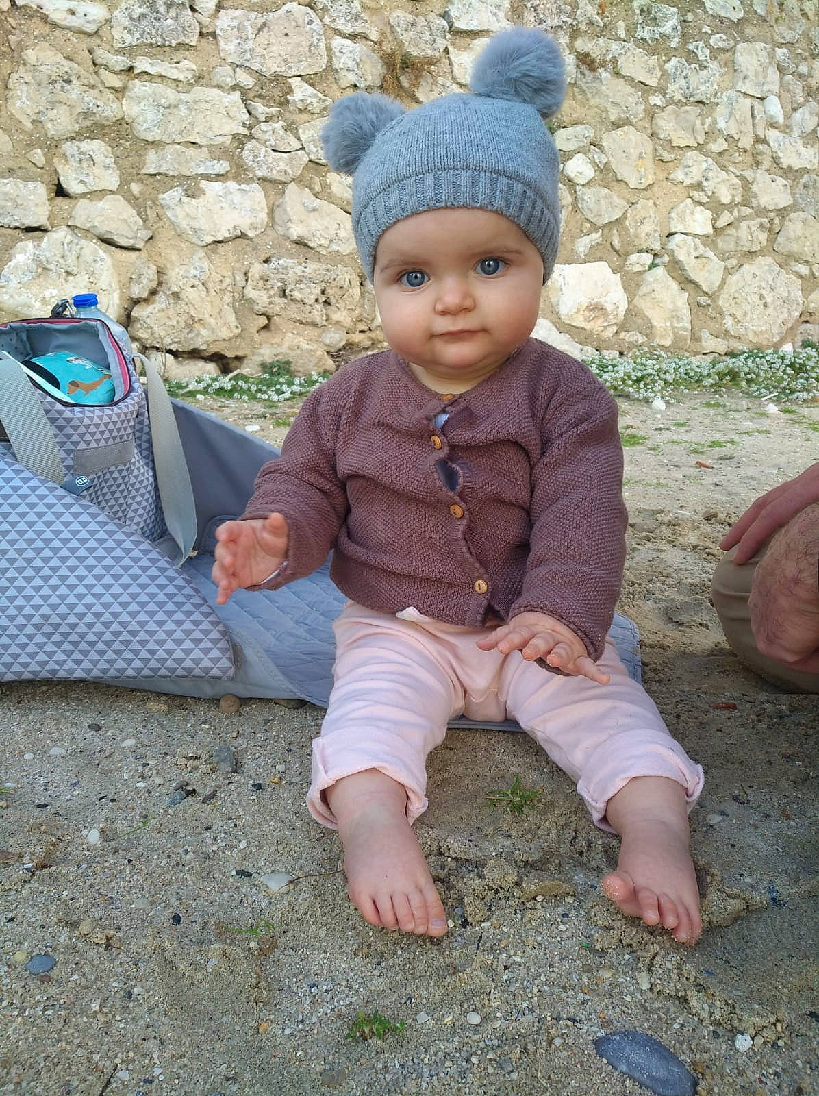 Emma a rejoint le concours — aidez-le/la à gagner de superbes lots ! baby, baby_toddler_clothing, barefoot, blue, cap, child, fashion_accessory, foot, fun, grass, hat, headwear, human_leg, knit_cap, pattern, person, sitting, sleeve, soil, toddler