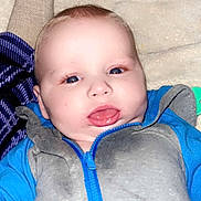Isaiah joined the competition — help win amazing prizes! baby, infant, blue_clothing, gray_clothing, zipper, face, tongue, blanket, soft_texture, lying_down, close_up, child, cute, indoors, happy, person, toddler, smiling, skin, head