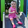 Margo joined the competition — help win amazing prizes! child, toddler, slide, playground, pink_clothing, pink_shoes, outdoor, daylight, happy, smiling, shorts, romper, plastic_slide, green, blue, trees, sunlight, person, face, fun