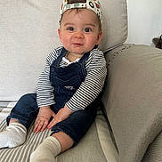 Lenny participe au concours pour gagner de l'argent avec cette photo : baby, cap, casual, child, couch, cute, denim_overalls, fashion, happy, home_interior, indoors, infant, person, playful, portrait, seated, smiling, socks, striped_blanket, striped_shirt