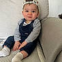 baby, cap, casual, child, couch, cute, denim_overalls, fashion, happy, home_interior, indoors, infant, person, playful, portrait, seated, smiling, socks, striped_blanket, striped_shirt