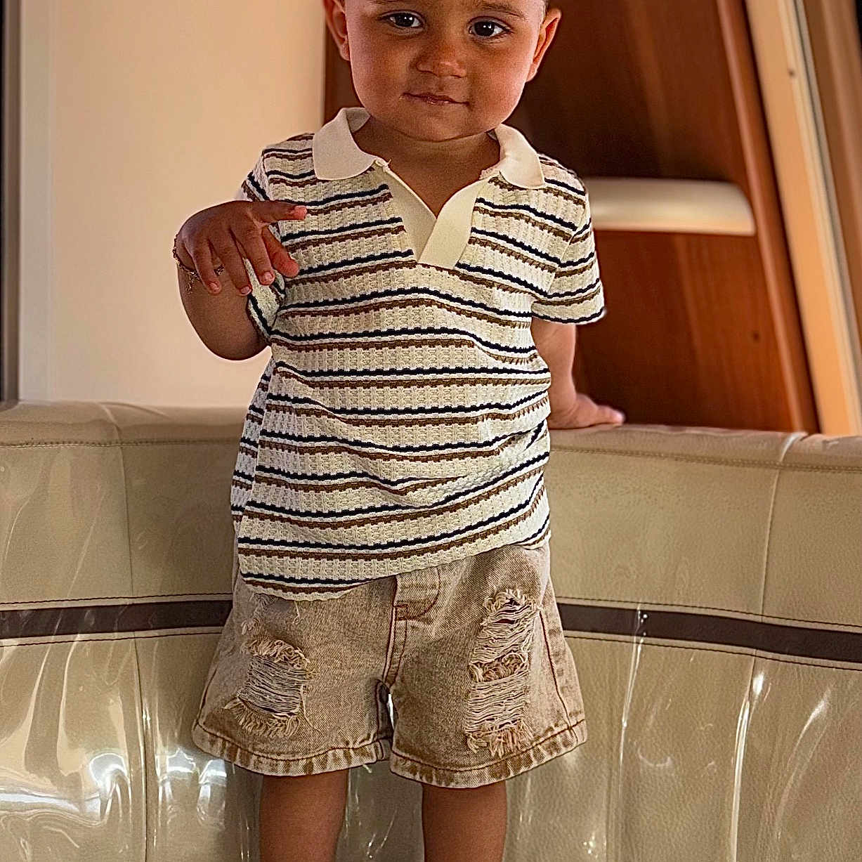 Konrad a rejoint le concours — aidez-le/la à gagner de superbes lots ! toddler, child, person, standing, striped_shirt, polo_shirt, denim_shorts, ripped_shorts, sneakers, white_shoes, couch, indoor, wood_paneling, smiling, short_hair, cute, fashion, casual_clothing, young_child, confident