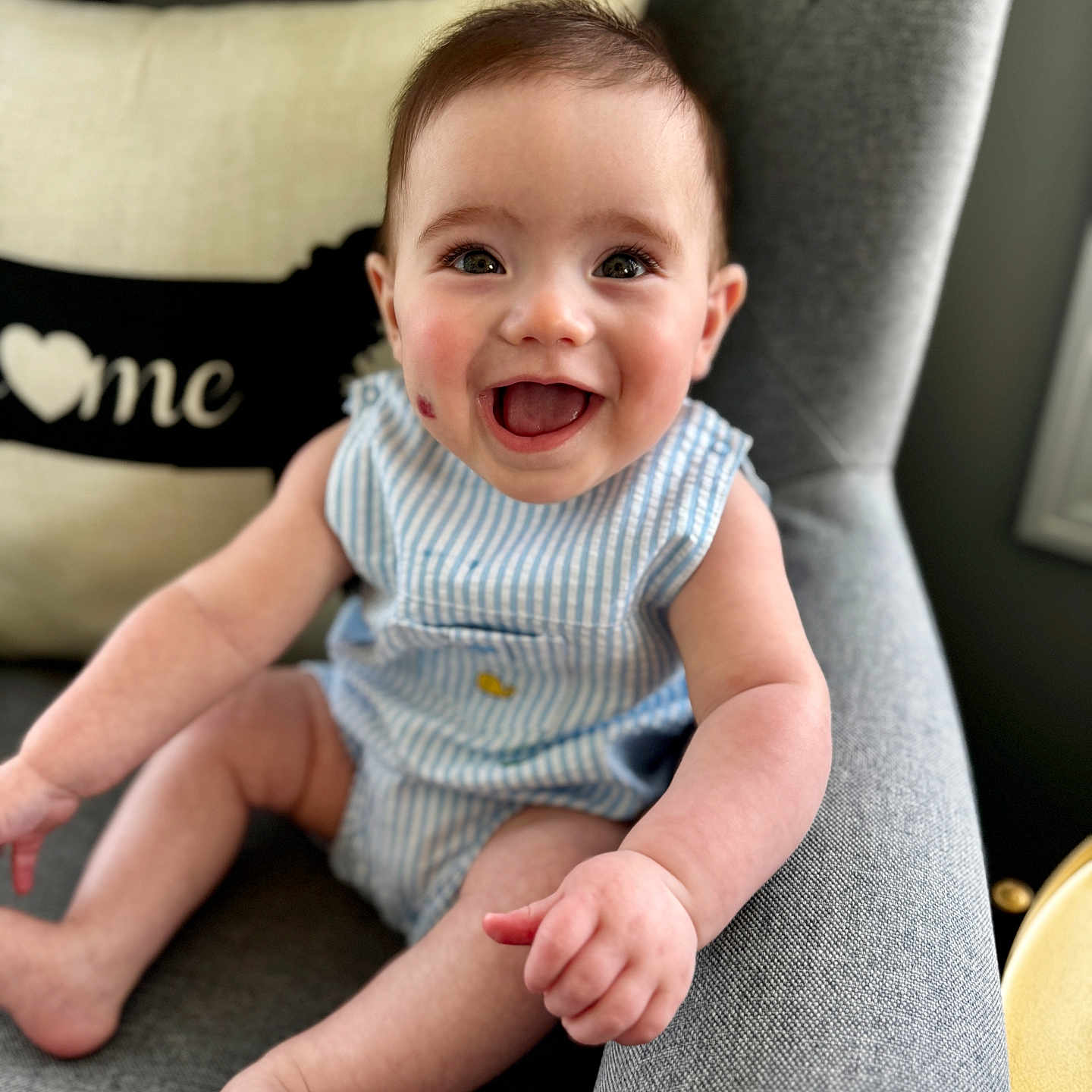 Bentley Orchard is registered to the contest to win money with this photo: arm, baby, blue_striped_outfit, chair, child, cushion, cute, expression, face, foot, happy, home, indoor, infant, leg, person, portrait, sitting, skin, smiling