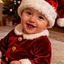 baby, celebration, child, christmas, cute, decorations, festive, fur_trim, gold_buttons, happy, holiday, indoor, infant, lights, portrait, red_clothing, santa_hat, seasonal, smile, tree
