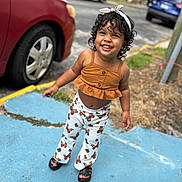 Nahomy joined the competition — help win amazing prizes! child, toddler, smiling, curly_hair, headband, orange_top, butterfly_pants, sandals, outdoor, sidewalk, car, parking_lot, concrete, joyful, happy, person, summer, cute, fashion, playful