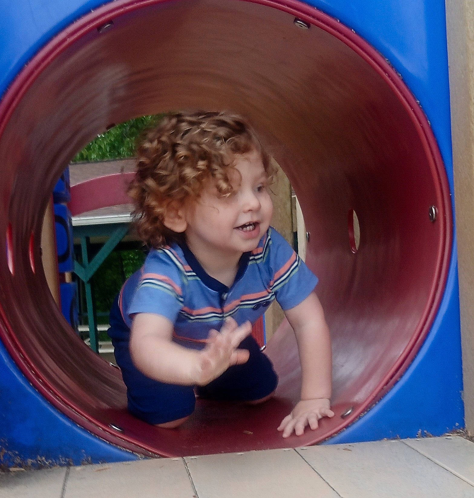 Jaxson is registered to the contest to win money with this photo: automotive_tire, baby_toddler_clothing, beauty, blue, child, circle, city, electric_blue, facial_expression, fun, leisure, outdoor_play_equipment, person, play, playground, public_space, recreation, smile, standing, t_shirt