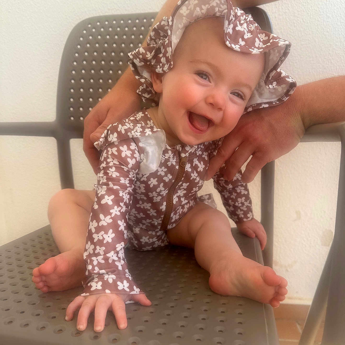Hattie is registered to the contest to win money with this photo: baby, chair, child, clothing, cute, expression, face, floral_pattern, foot, hand, happy, hat, indoor, infant, joy, person, sitting, skin, smiling, support