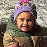 child, smiling, winter_clothing, hat, pom_pom, minnie_mouse, snow, outdoor, cold_weather, jacket, colorful, happy, face, portrait, cute, young_child, playful, snowy_ground, fun, warm