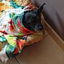 dog, blanket, pet_bed, tile_floor, indoor, resting, cozy, black_dog, fur, animal, colorful, patterned, comfort, sleepy, quiet, home, relaxed, wrapped, nap, wall