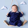 baby, infant, sleeping, swing, wooden_swing, blue_background, knitwear, navy_blue, cute, peaceful, clouds, felt_clouds, soft_lighting, portrait, child, newborn, indoors, handheld, cozy, adorable