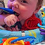 Greyson is registered to the contest to win money with this photo: baby, infant, child, toys, teething, playmat, colorful, closeup, hand, face, smile, indoors, chewing, plastic, red, blue, yellow, cute, happy, young
