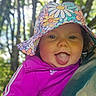 Evalyn joined the competition — help win amazing prizes! baby, child, tongue_out, hat, floral_hat, purple_jacket, outdoor, forest, trees, nature, cute, playful, smiling, person, headwear, portrait, happy, infant, apparel, sunlight