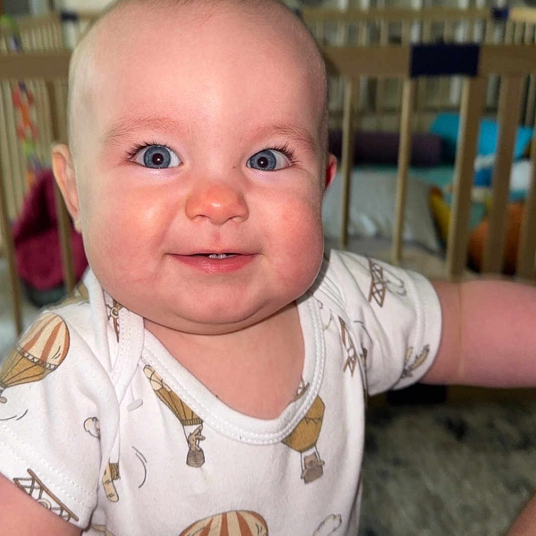 William joined the competition — help win amazing prizes! arm, baby, blue_eyes, child, cozy, crib, cute, expression, face, furniture, happy, home, hot_air_balloon, indoor, infant, onesie, person, portrait, skin, smiling