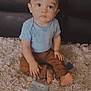 Isaiah joined the competition — help win amazing prizes! toddler, child, blue_shirt, brown_pants, barefoot, rug, toy, indoor, curious, sitting, floor, carpet, person, home, young_child, cute, face, looking_up, living_room, soft_lighting