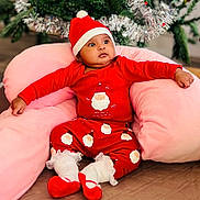 Mary-Abilene a rejoint le concours — aidez-le/la à gagner de superbes lots ! baby, child, christmas, holiday, festive_clothing, red_pajamas, santa_hat, pink_cushion, indoor, decorated_tree, greenery, celebration, cute, infant, smiling, soft_texture, holiday_season, cozy, portrait, relaxed