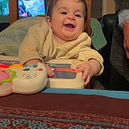 Lyzéa participe au concours pour gagner de l'argent avec cette photo : baby, child, clothing, cute, expression, face, furniture, happy, high_chair, home, indoor, infant, person, playing, sitting, smiling, table, toy, wooden_chair, young_child