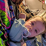 Kida is registered to the contest to win money with this photo: toddler, child, pacifier, person, adult, glasses, indoor, clothing, face, curly_hair, decorations, holiday, wall_clock, couch, blanket, relaxing, home, family, casual, portrait