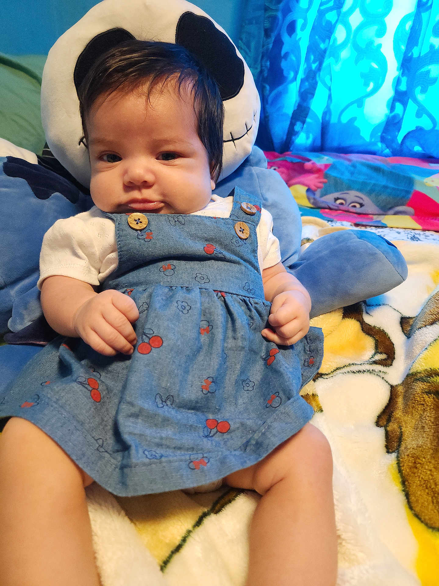 Hazel is registered to the contest to win money with this photo: baby, child, blue_dress, plush_toy, blanket, indoor, cute, sitting, face, hands, legs, button, pattern, fabric, toy, bedroom, curtain, colorful, soft, comfort