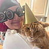 cat, orange_cat, fluffy, long_hair, pet, party_hat, new_year, celebration, human, person, portrait, close_up, indoors, kitchen, cabinets, glasses, costume, whiskers, green_eyes, festive