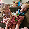 baby, children, couch, dress, family, happy, home, indoors, living_room, pacifier, playroom, portrait, preschooler, shirt, siblings, sitting, smiling, stuffed_animal, toddler, toy_kitchen