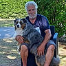 animal, australian_shepherd, beard, casual_clothing, chair, dog, friendship, fur, grass, greenery, man, nature, outdoor, pet, portrait, relaxation, shorts, sitting, summer, sunlight