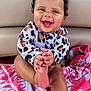 baby, child, curly_hair, smiling, happy, towel, pink, patterned, clothing, foot, hand, face, sitting, indoors, cute, infant, skin, person, playful, joyful